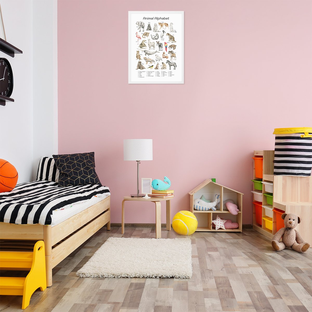 Plakat dla dziewczynek z alfabetem i dzikimi zwierzętami w białej ramce powieszony na ścianie w pokoju dziecięcym