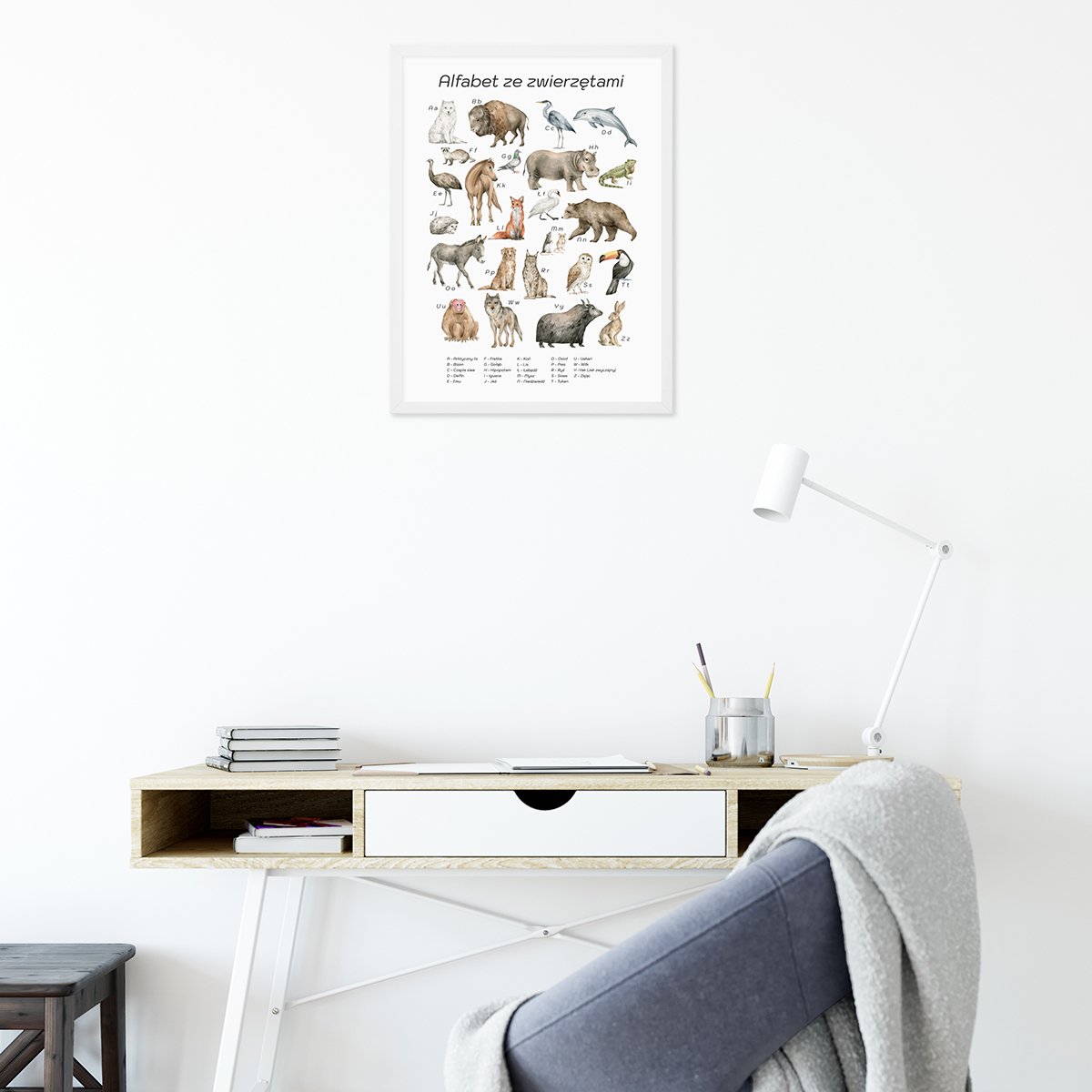 Plakat do pokoju maluszka z alfabetem i zwierzętami w białej ramce powieszony nad dziecięcym biurkiem