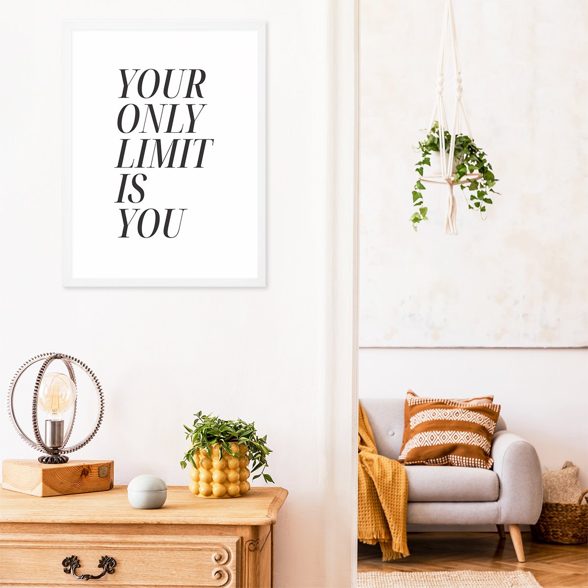 Plakat z motywacyjnym napisem do przedpokoju oprawiony w biała ramkę zawieszony nad komodą