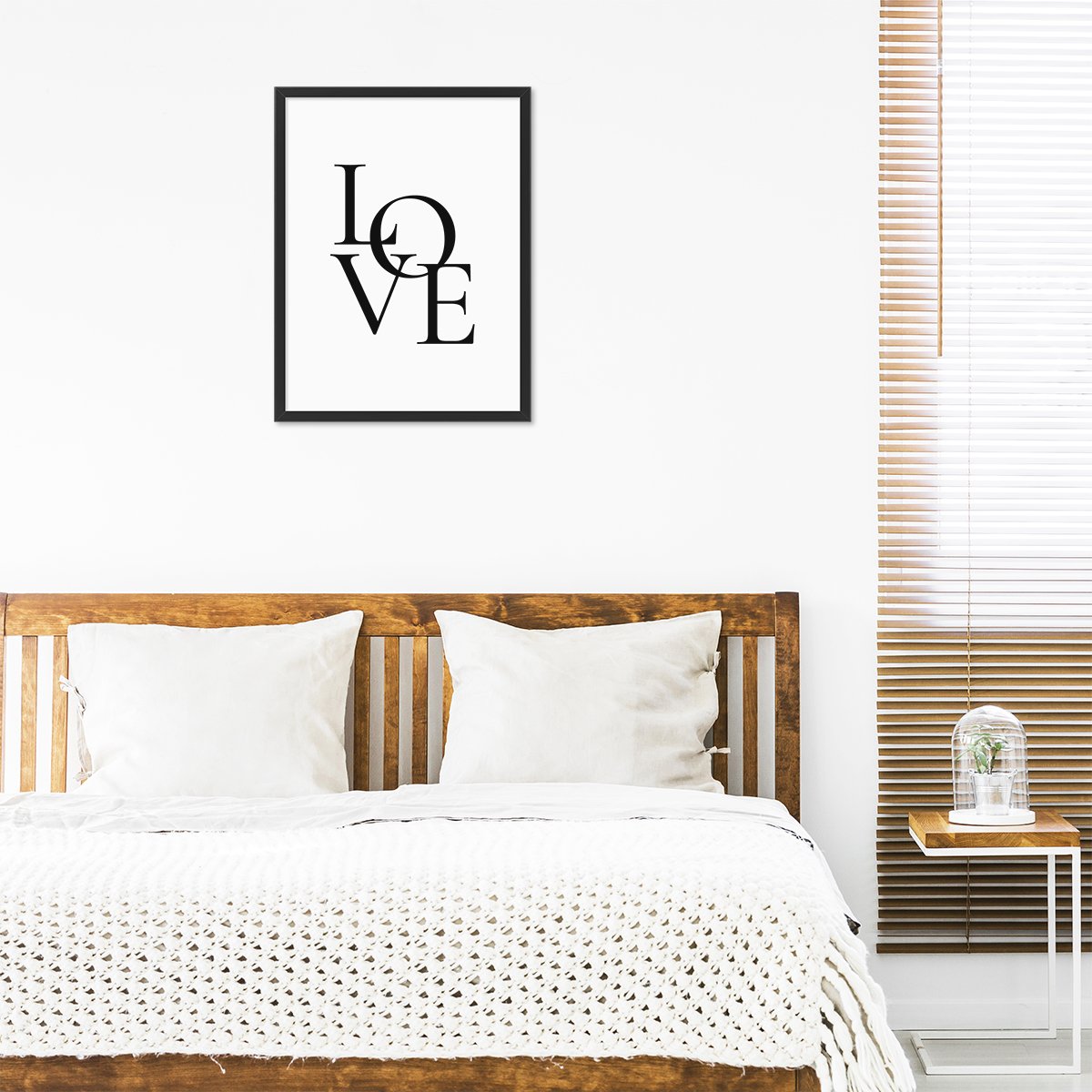 Plakat z napisem love do sypialni w czarnej ramce powieszony nad łóżkiem