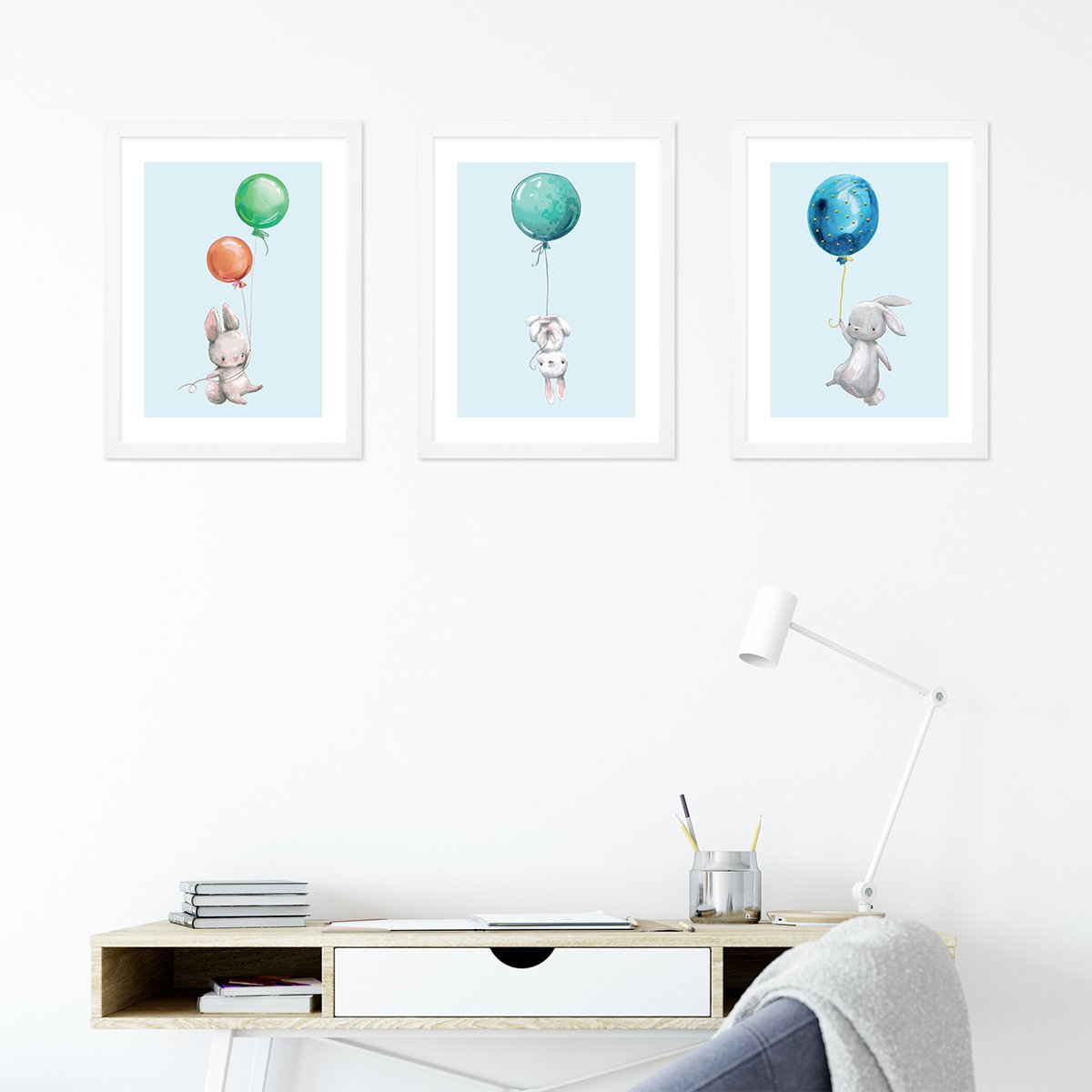 Plakaty dla dzieci króliczki lecące na kolorowych balonach na niebieskim tle powieszone nad biurkiem w pokoju dziecięcym#kolor_kolorowy