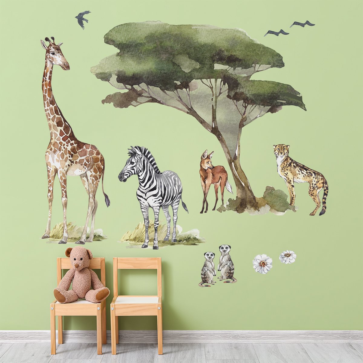 Naklejki na ścianę dla dziewczynki z żyrafą i zwierzętami afrykańskimi naklejone na ścianie nad stolikiem z krzesełkami w pokoju dziecięcym