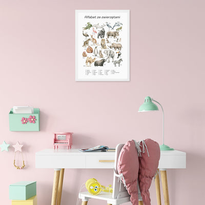 Plakat na ścianę dla dziewczynki z alfabetem i dzikimi zwierzętami  w białej ramce powieszony nad biurkiem w pokoju dziecięcym