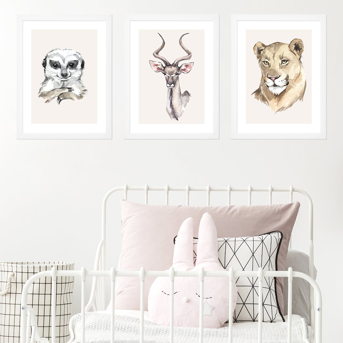 Plakaty z surykatką , gazelą i lwicą dla dziewczynki oprawione w białe ramie zawieszone na ścianie za łóżkiem
