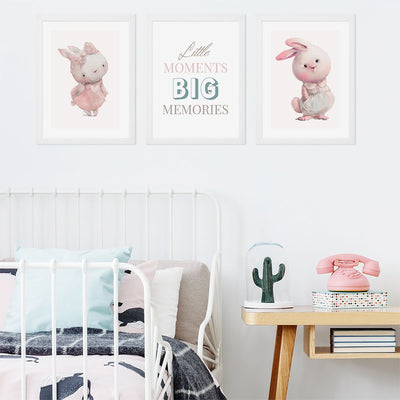 Plakaty na ścianę dla dziewczynki utrzymane w pastelowych tonach z króliczkami i napis w białych ramkach powieszone nad dziecięcym łóżkiem